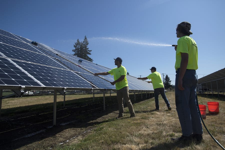 Rafer Stromme, from left, Nick Neathamer and Spencer Black, members of the student grounds crew, clean solar panels at Clark Public Utilities’ operations center in Vancouver. In 2015, Clark Public Utilities launched a program that prompted about 700 customers to invest in the county’s largest solar array. The solar panels need to be cleaned to remove dust to maximize energy production, especially in the summer months.