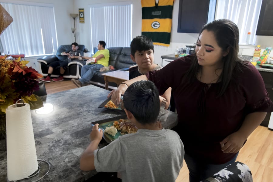 Giovanni Valtierra, 14, left, waits for Vanessa Contreras to finish pouring teriyaki sauce before eating dinner with the rest of his family at their Vancouver apartment on Tuesday evening.