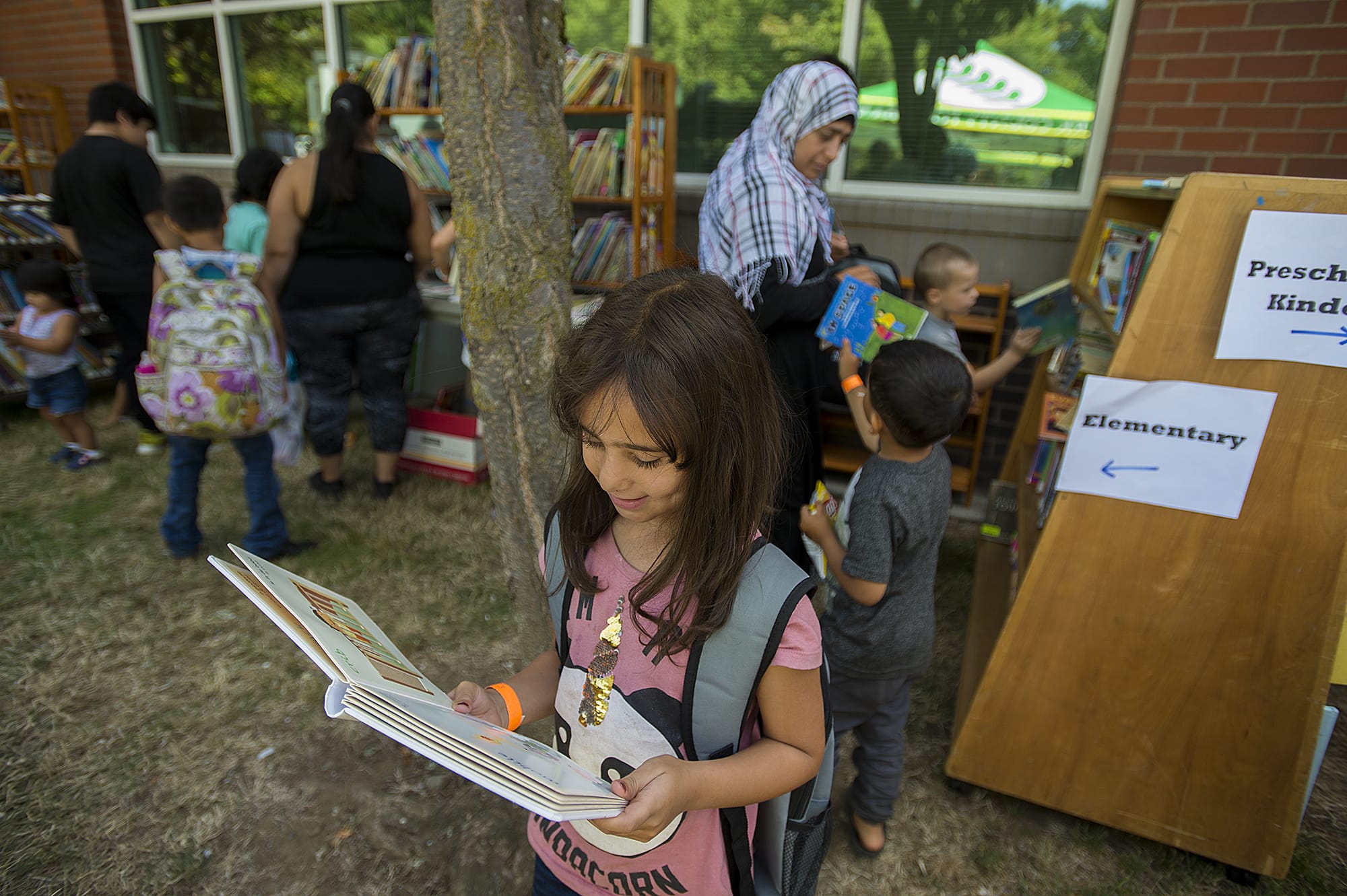 Vancouver resident Shahed Alhariri, 8, dives into a good story while visiting the free book nook with her family during the annual back-to-school readiness event at Hudson’s Bay High School on Wednesday afternoon, Aug. 14, 2019.