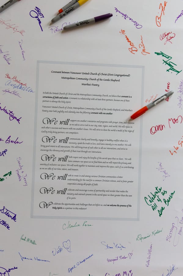 Churchgoers sign a poster Sunday featuring the new covenant between Vancouver United Church of Christ, Metropolitan Community Church of the Gentle Shepherd and Martha’s Pantry.