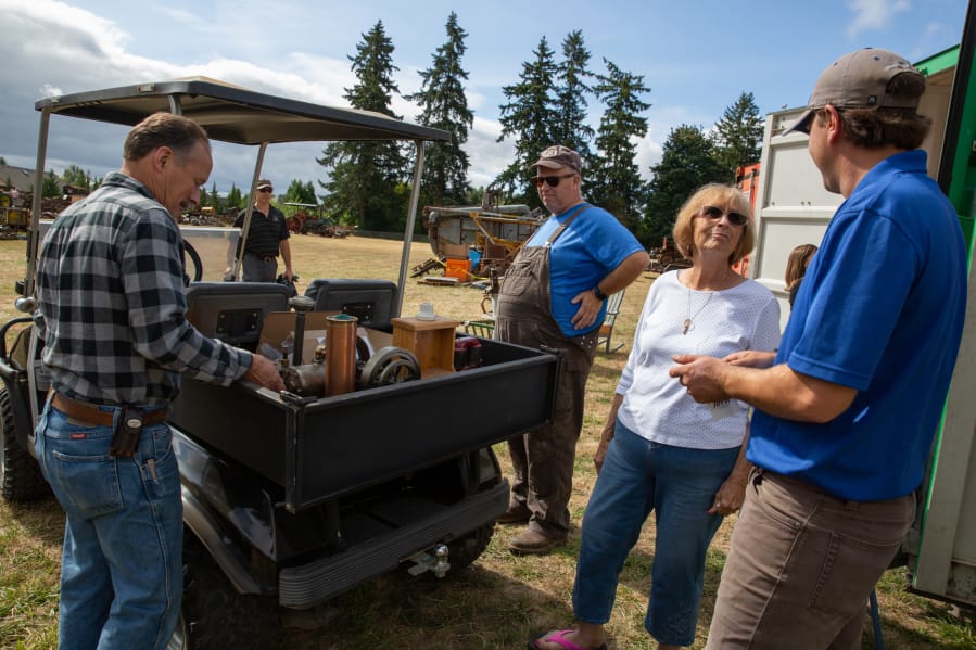 Marcella Schurman, second from right, talks with Aumann Auctions staff after finding an engine her late husband Alan built by hand, at her property in Ridgefield on Saturday.