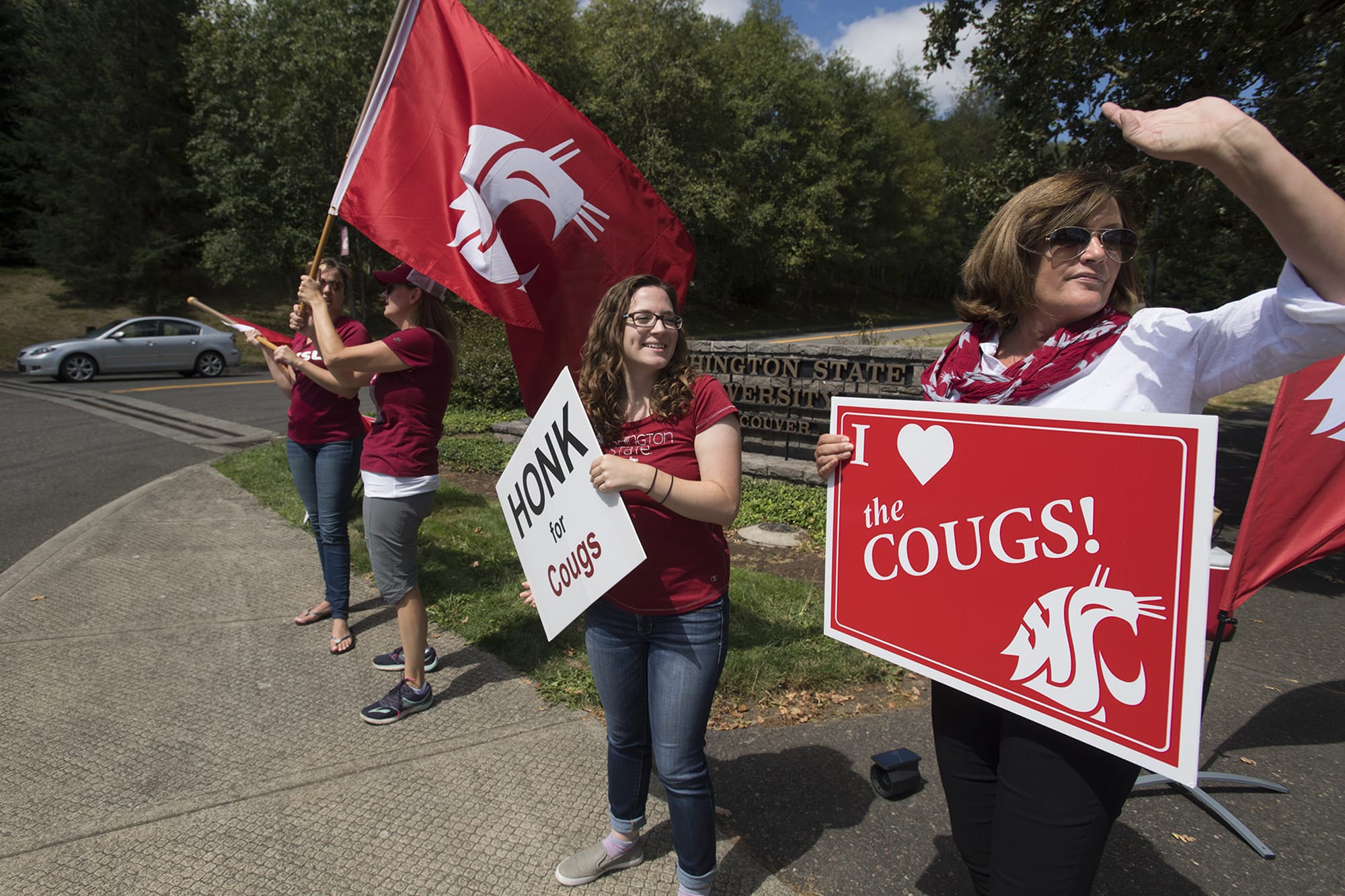 Jessica Wells, program coordinator for development and alumni relations, center, joins Lisa Abrahamsson, assistant director of development and alumni relations, right, as they welcome incoming students on their first day back to campus at Washington State University Vancouver on Monday afternoon.
