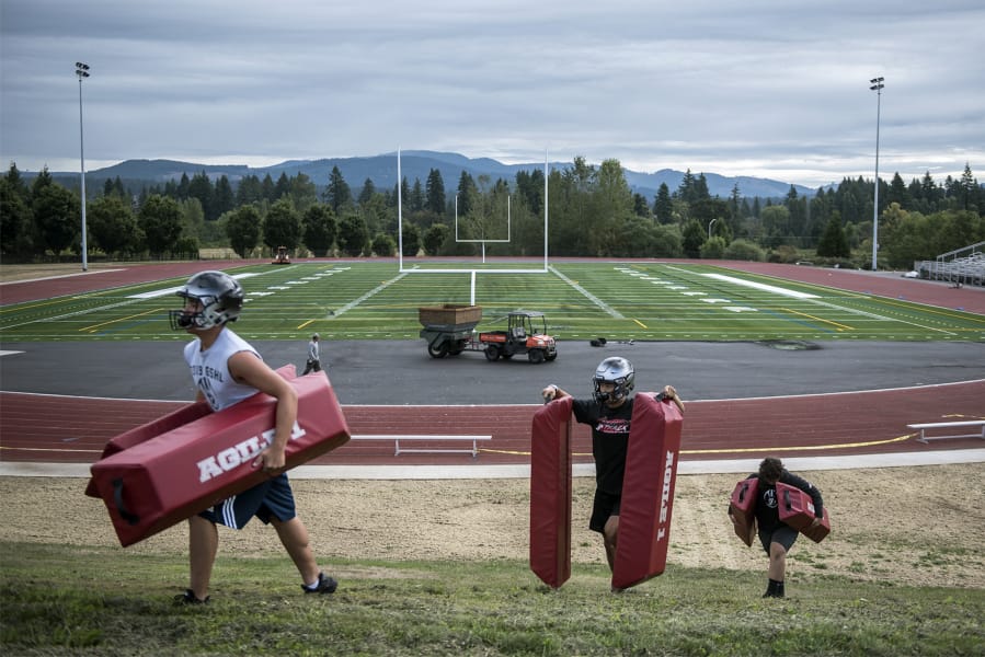Union players carry drill obstacles from the Union High football field during the first fall practice of the year on Wednesday, Aug. 22, 2019.