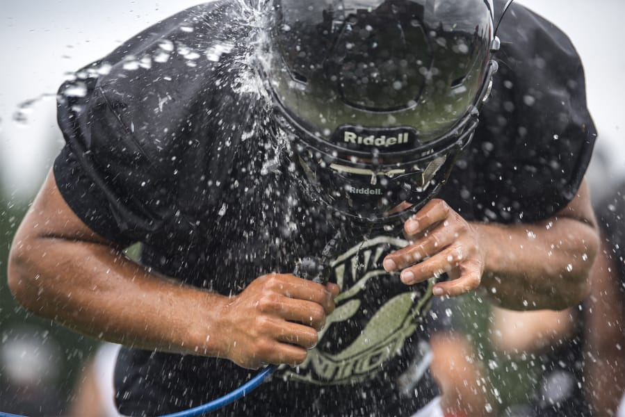 A Union players srays water on his face during the first fall practice at Union High School on Wednesday, Aug. 22, 2019.