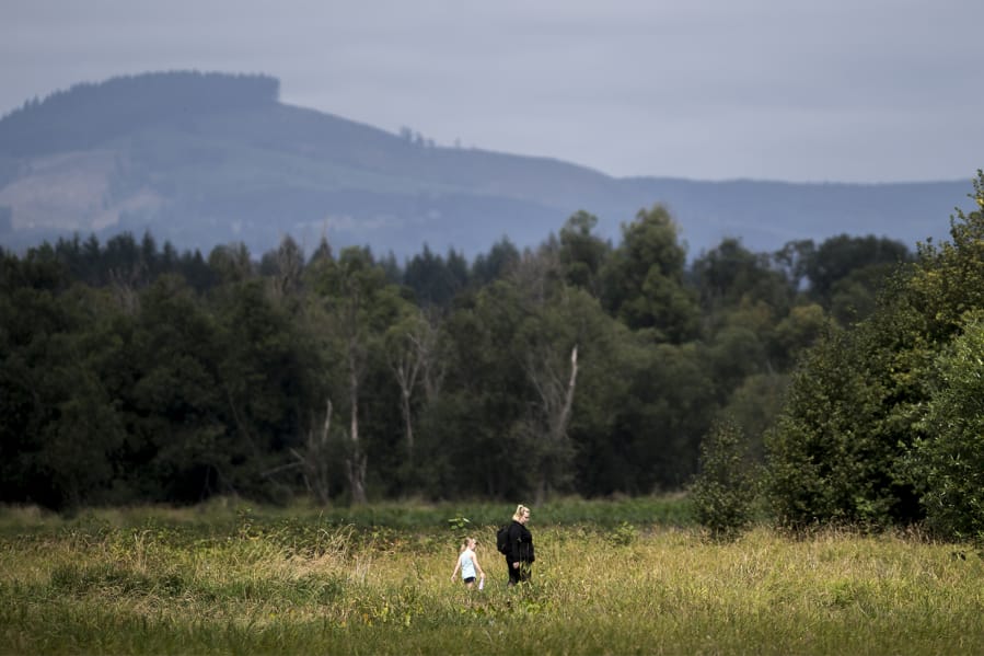 Maxine Deschand, 6, left, and her mother, Brianna Deschand, walk through the Ridgefield National Wildlife Refuge on Thursday. The refuge has proved a crucial habitat for the region’s endangered and threatened species, helping populations such as the Columbian white-tailed deer rebound.