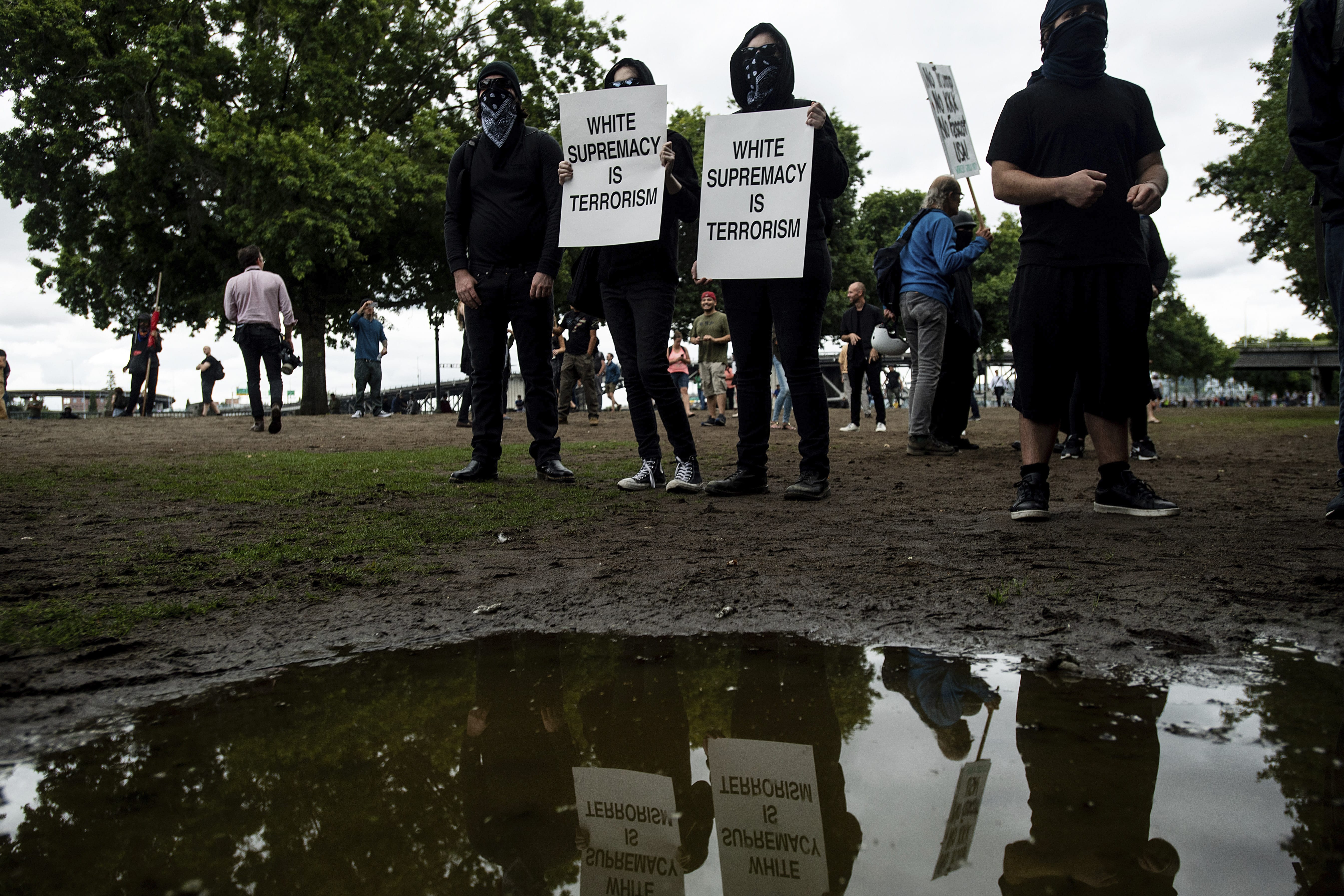 Black-clad protesters, gathered to oppose conservative groups staging an "End Domestic Terrorism" rally, hold signs in Portland, Ore., on Saturday, Aug. 17, 2019. Police have mobilized to prevent clashes between conservative groups and counter-protesters who plan to converge in the city.