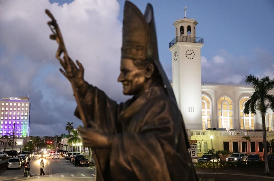 A statue of Pope John Paul II stands outside the island’s main cathedral, Dulce Nombre de Maria Cathedral-Basilica, during a Mass in Hagatna, Guam, Tuesday, May 7, 2019. Those old enough to remember often cite the pontiff’s visit to the island in 1981 as the most thrilling event of their lifetimes, memorialized by the bronze statue of the now-sainted pope designed to slowly rotate on a concrete pedestal.