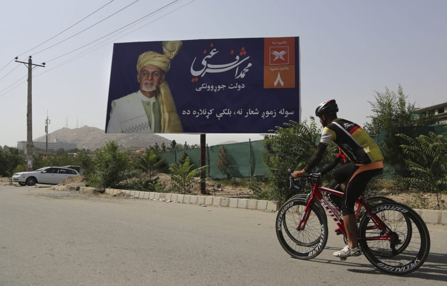 Afghan men rides cycle past an election hoarding of a presidential candidate Ashraf Ghani in Kabul,Afghanistan Friday, Aug. 9, 2019.Afghanistan faces a presidential election next month but few believe the vote will take place as the United States and the Taliban inch closer to a deal that could end the nearly 18-year war but bring uncertainty about almost everything else.