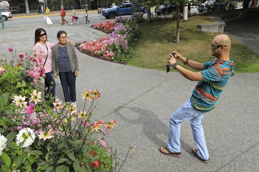 Junar Lim takes photos of Ziah Lim, left, and Arsenia Lim, all of Cavite, the Philippines, at gardens in Town Square in Anchorage, Alaska, Thursday, Aug. 15, 2019. Alaska recorded its warmest month ever in July and hot, dry weather has continued in Anchorage and much of the region south of the Alaska Range.