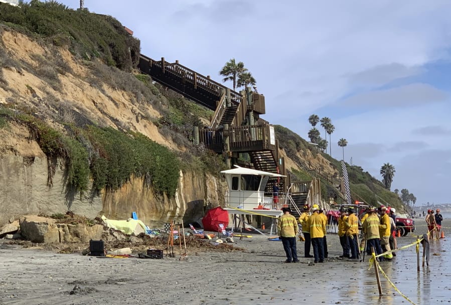 Lifeguards and search and rescue personnel work at the site of a cliff collapse at a popular beach Friday in Encinitas, Calif. At least one person was killed.