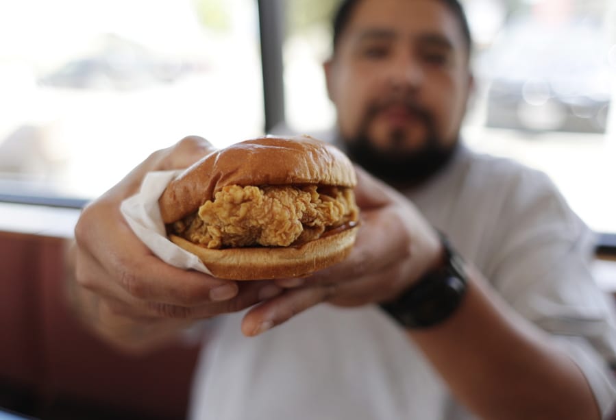 Randy Estrada holds up his chicken sandwich Thursday at a Popeyes in Kyle, Texas.