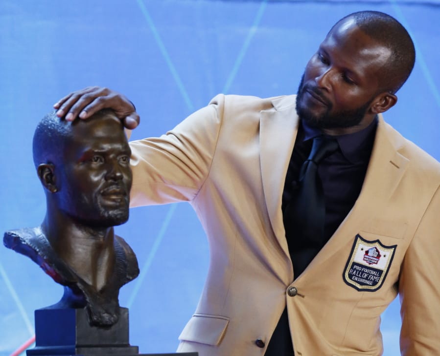 Former NFL player Champ Bailey touches a bust of himself during the induction ceremony at the Pro Football Hall of Fame, Saturday, Aug. 3, 2019, in Canton, Ohio.