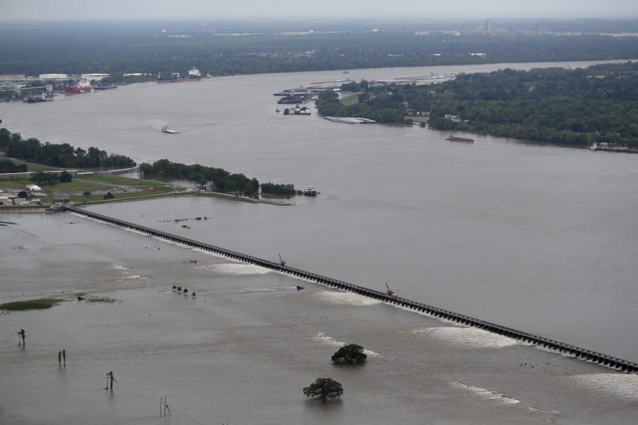 File - In this May 10, 2019 file photo, workers open bays of the Bonnet Carre Spillway, to divert rising water from the Mississippi River to Lake Pontchartrain, upriver from New Orleans, in Norco, La. The river that drains much of the flood-soaked United States is running far higher than normal this hurricane season, menacing New Orleans in multiple ways. One continuing concern is the massive volume of water that for months has been pushing against levees protecting a city that’s mostly below sea level.