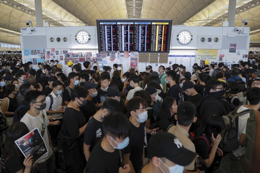 Protesters gather near a flights information board during a protest at the Hong Kong International Airport, Monday, Aug. 12, 2019. One of the world’s busiest airports canceled all flights after thousands of Hong Kong pro-democracy protesters crowded into the main terminal Monday afternoon.
