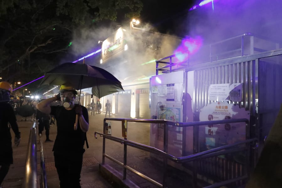 Protesters react to tear gas fired near the Tsim Sha Tsui police station in Hong Kong on Saturday, Aug. 10, 2019. Hong Kong is in its ninth week of demonstrations that began in response to a proposed extradition law but have expanded to include other grievances and demands for more democratic freedoms.