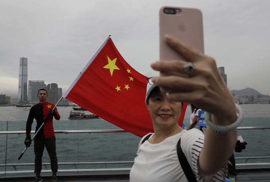 In this Saturday, Aug. 17, 2019 file photo, pro-China supporters take a selfie with a Chinese national flag to support police and anti-violence during a rally at a park in Hong Kong. Twitter said Monday it has suspended more than 200,000 accounts that it believes were part of a Chinese government influence campaign targeting the protest movement in Hong Kong.
