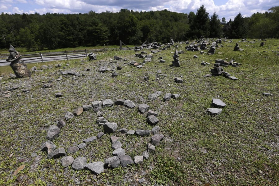 In this Wednesday, July 24, 2019, photo, a flat piece of ground and rock cairns are all that remain of the stage of the 1969 Woodstock Music and Arts Fair in Bethel, N.Y. Woodstock was staged 80 miles (130 kilometers) northwest of New York City on a bucolic hillside owned by dairy farmer Max Yasgur. It was a great spot for peaceful vibes, but miserable for handling the hordes coming in by car.