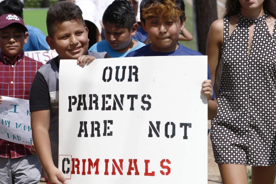 FILE - In this Aug. 11, 2019, file photo, children of mainly Latino immigrant parents hold signs in support of them and those individuals picked up during an immigration raid at a food processing plant, during a protest march to the Madison County Courthouse in Canton, Miss. Unauthorized workers are jailed or deported, while the managers and business owners who profit from their labor often aren’t. Under President Donald Trump, the numbers of owners and managers facing criminal charges for employing unauthorized workers have stayed almost the same. (AP Photo/Rogelio V.