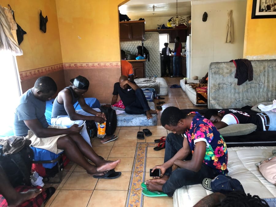 In this July 28, 2019, photo, Cameroonians wait in a rented apartment in Tijuana, Mexico, until their names are called to claim asylum in the U.S. The Cameroonian men who share 10 mattresses on the floor of a third-floor apartment above a barber shop walk every morning to the busiest U.S. border crossing with Mexico, hoping against all odds that it will be their lucky day to claim asylum. Their unlikely bet is that a sympathetic Mexican official will somehow find a spot for them.