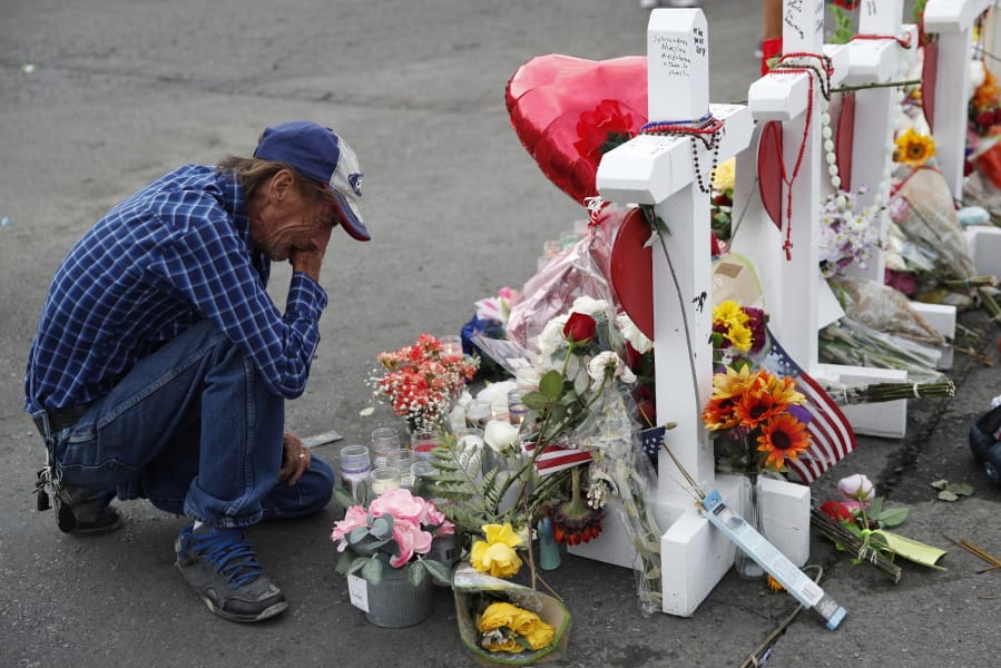 FILE - In this Aug. 6, 2019 file photo, Antonio Basco cries beside a cross at a makeshift memorial near the scene of a mass shooting at a shopping complex, in El Paso, Texas. Basco, whose 63-year-old wife was among the Texas mass shooting victims says he has no other family and welcomes anyone wanting to attend her services in El Paso. Margie Reckard was among 22 people fatally shot on Aug. 3 at a the Walmart. Reckard and Basco were married 22 years.