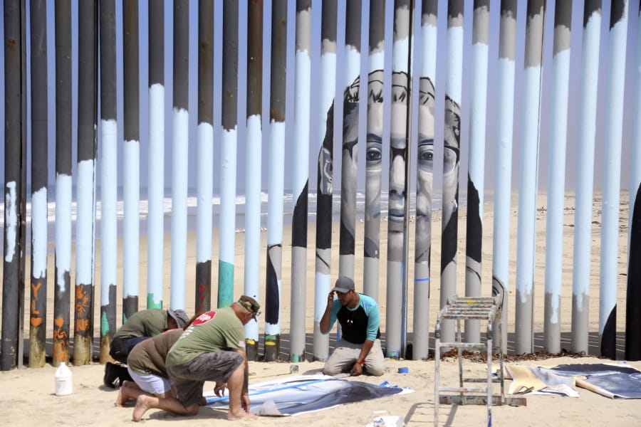Volunteers help install a new mural on the Mexican side of a border wall that shows faces of people deported from the U.S. with barcodes that activate first-person narratives on visitors’ phones, in Tijuana, Mexico, Friday, Aug. 9, 2019. Lizbeth De La Cruz Santana conceived the interactive mural Her project blends Mexico’s rich history of muralists with what can loosely be called interactive or performance art on the U.S.-Mexico border.