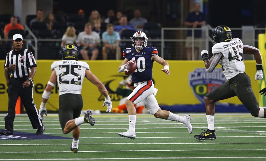 Auburn quarterback Bo Nix (10) looks to pass as Oregon safety Brady Breeze (25) and Oregon defensive end Gus Cumberlander (45) pursue during the first half of an NCAA college football game, Saturday, Aug. 31, 2019, in Arlington, Texas.