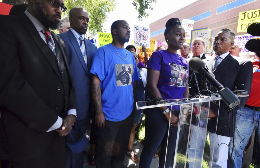 FILE - In this Aug. 13, 2019 file photo, Delisha Searcy, mother of De’Von Bailey, at podium, speaks at a news conference in front of the Colorado Springs Police Department Police Operations Center in Colorado Springs, Colo. Greg Bailey, third from left, De’Von Bailey’s father, stands next to Searcy. Police body camera video released Thursday, Aug. 15, 2019 shows De’Von Bailey being shot by police while running away.