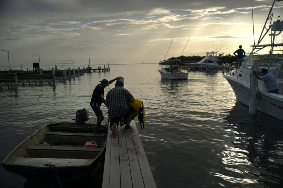 People arrive to a private harbor to move boats away for protection ahead of the arrival of Tropical Storm Dorian in Boqueron, Puerto Rico, Tuesday, Aug. 27, 2019.