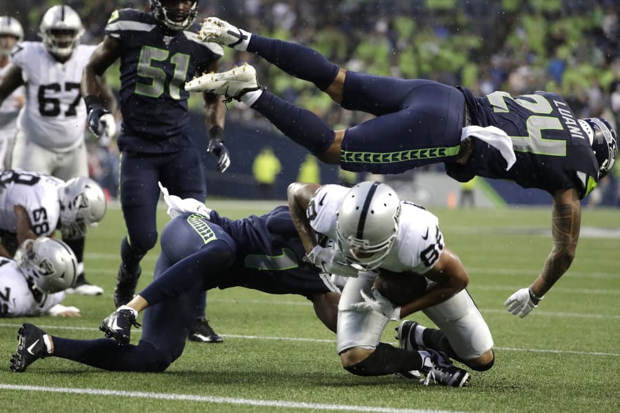 Seattle Seahawks defensive back Shalom Luani (24) flies over Oakland Raiders wide receiver Marcell Ateman (88) after Ateman made a catch during the first half of an NFL football preseason game Thursday, Aug. 29, 2019, in Seattle.