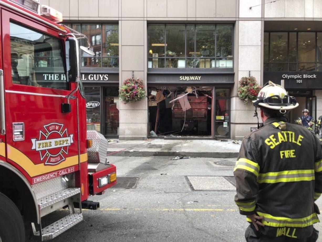 In this Monday, Aug. 19, 2019, photo provided by the Seattle Fire Department, a firefighter looks on at the scene of where a dump truck crashed into a Subway restaurant in Seattle’s historic Pioneer Square district, injuring five people. The Seattle Fire Department said four of the people had serious injuries and all were taken to a nearby hospital Monday morning. Seattle Police say the truck “allegedly suffered a catastrophic mechanical failure,” coming to rest completely inside the Subway, having shattered the entire front window of the store.