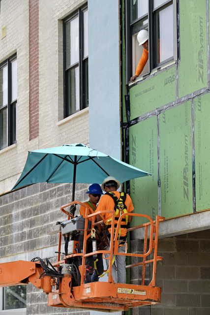 A construction crew keeps out of the sun with a sun umbrella on their boom lift as they work on an apartment building along S. Jefferson Davis Parkway in New Orleans, La. Tuesday, Aug. 13, 2019.