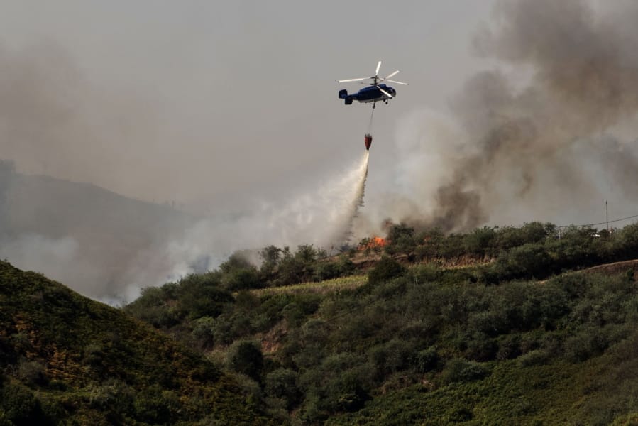 A helicopter operates over a wildfire in Canary Islands, Spain, Monday, Aug. 19, 2019. A wildfire in Spain’s Canary Islands threw flames 50 meters (160 feet) into the air and has forced emergency services to evacuate more than 8,000 people, authorities said Monday.