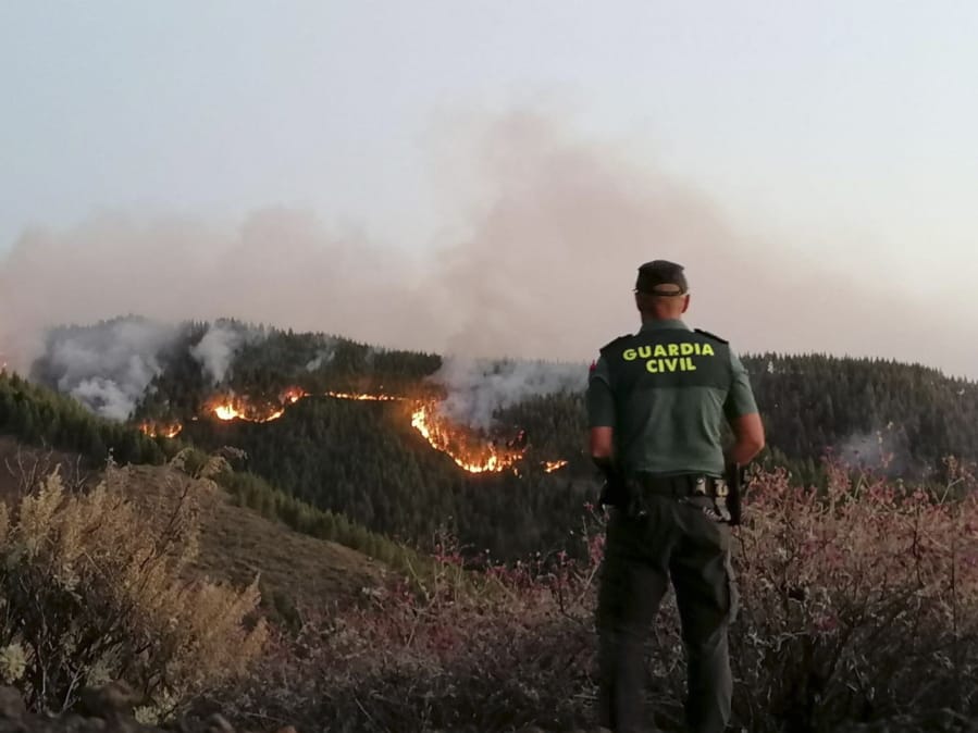 In this photo issued by the Guardia Civil, an officer looks at a forest fire in Gran Canaria, Spain, on Saturday Aug. 11, 2019. Spanish authorities say a wildfire on the Canary Island of Gran Canaria has burned 1,000 hectares (2,470 acres) and has forced the evacuation of 1,000 residents.