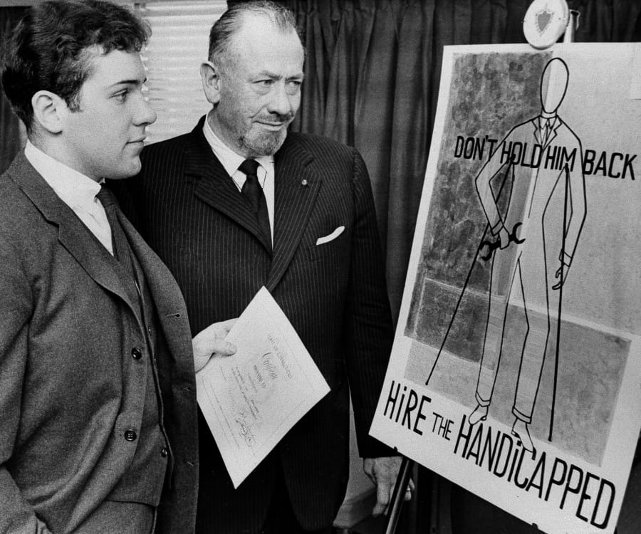FILE - In this March 22, 1963, file photo, Nobel prize-winning author John Steinbeck, right, admires a prize-winning poster by his son, Thomas Steinbeck in Hartford, Conn. A three-judge panel of the Ninth U.S. Circuit Court of Appeals will be in Alaska’s largest city on Tuesday, Aug. 6, 2019, to hear arguments in an appeal by the estate of Steinbeck’s late son, Thomas Steinbeck, over a 2017 ruling in California. In that case, a federal jury awarded the author’s stepdaughter Waverly Scott Kaffaga, more than $13 million in a lawsuit claiming Steinbeck’s son and daughter-in-law impeded film adaptations of the iconic works.