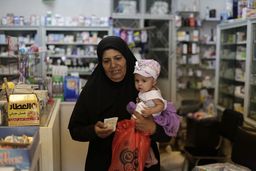 In this Wednesday, July 24, 2019 photo, a Syrian woman leaves a pharmacy after buying medicine in the Syrian capital, Damascus. Syrians say it’s even harder now to make ends meet than it was during the height of their country’s civil war because of intensified U.S and European sanctions. Prices have leaped because of restrictions on oil imports, the value of the currency has plunged in recent months. Most of the country is now below the poverty line, earning less than $100 a month.