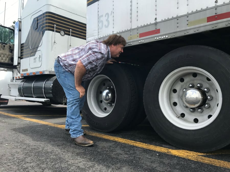 In this June 13, 2019 photo, truck driver Terry Button looks over his trailer during at stop in Opal, Va. The Trump administration has moved a step closer to relaxing federal regulations governing the amount of time truck drivers can spend behind the wheel.