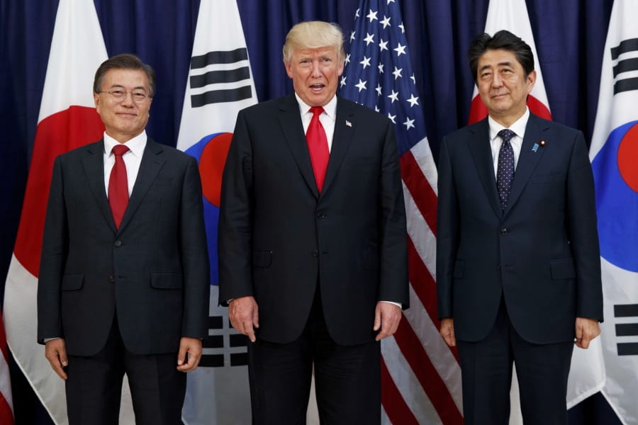 FILE - In this July 6, 2017, file photo, U.S. President Donald Trump, center, meets with Japanese Prime Minister Shinzo Abe, right, and South Korean President Moon Jae-in before the Northeast Asia Security dinner at the U.S. Consulate General Hamburg in Germany. In August 2019, Trump angered some Asian American voters after the New York Post reported that he mocked the accents of Moon and Abe at a fundraiser in the Hamptons.