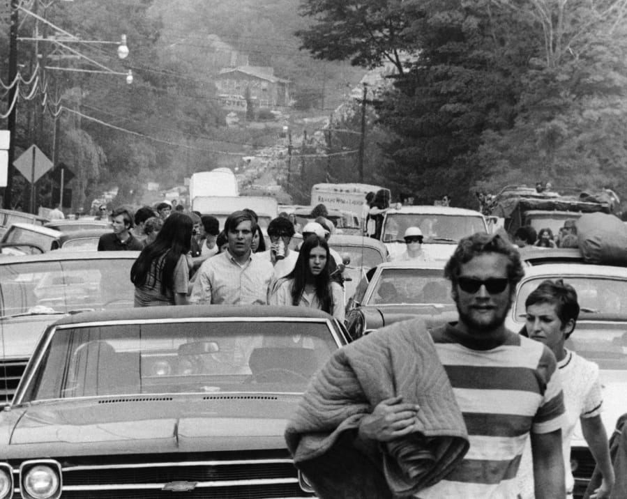 FILE - In this Aug. 15, 1969 file photo, concert goers abandon their trucks, cars and buses as thousands try to reach the Woodstock Music and Art Festival at White Lake in Bethel, N.Y. Although Arlo Guthrie famously announced from the festival stage that “The New York State Thruway is closed, man,” that wasn’t exactly the case. Police closed at least one thruway exit east of the festival to stem the source of a blockbuster traffic jam around the site. The New York Daily News reported on Aug. 16 that cars were being delayed by as much as eight hours between New York City and the concert site - a distance of less than 100 miles.