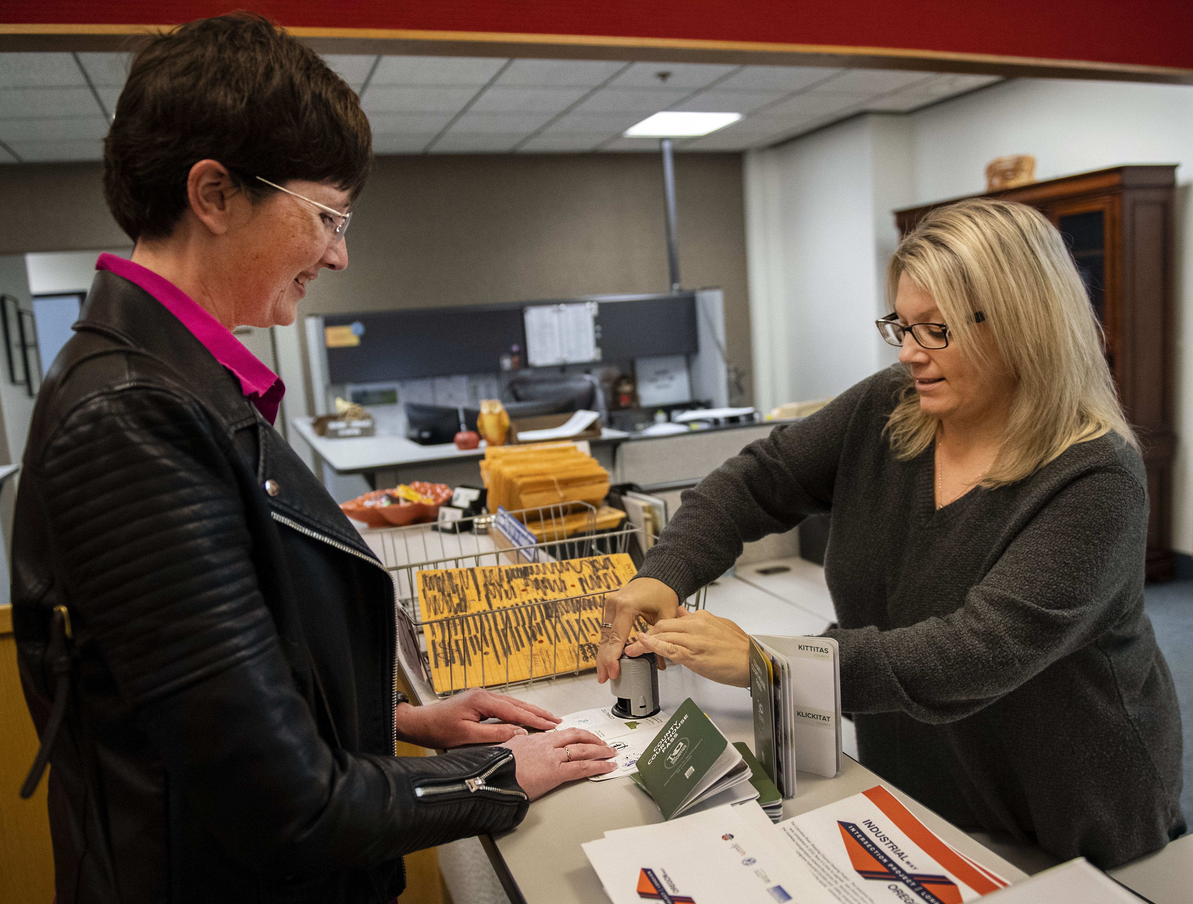 Winlock resident Lindsey Pollock, left, receives her final stamp in her completed Washington county passport from assistant clerk Lisa Huckleberry at the Cowlitz Commissioner in Kelso Monday afternoon.