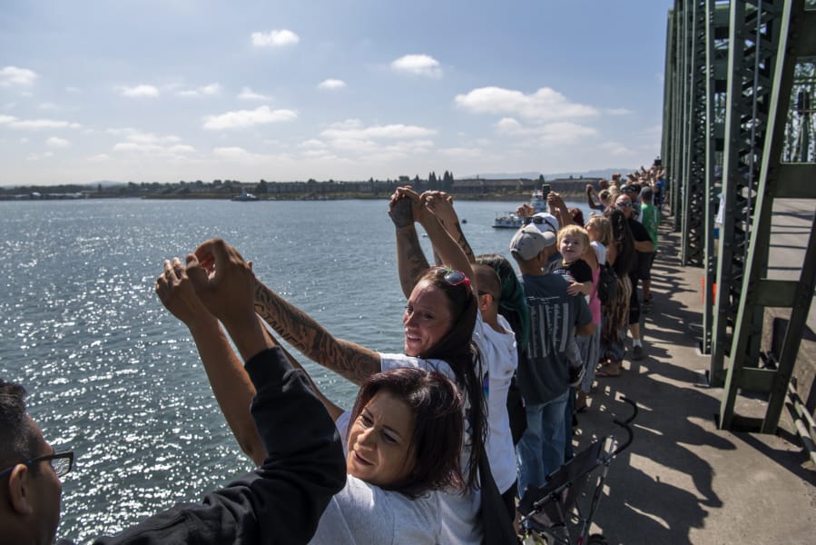 Attendees hold their hands up and recite the Serenity Prayer during Hands Across the Bridge on the Interstate 5 Bridge on Monday. This day marked the 19th anniversary of the event, in which people in recovery come together to share their stories and celebrate sobriety.
