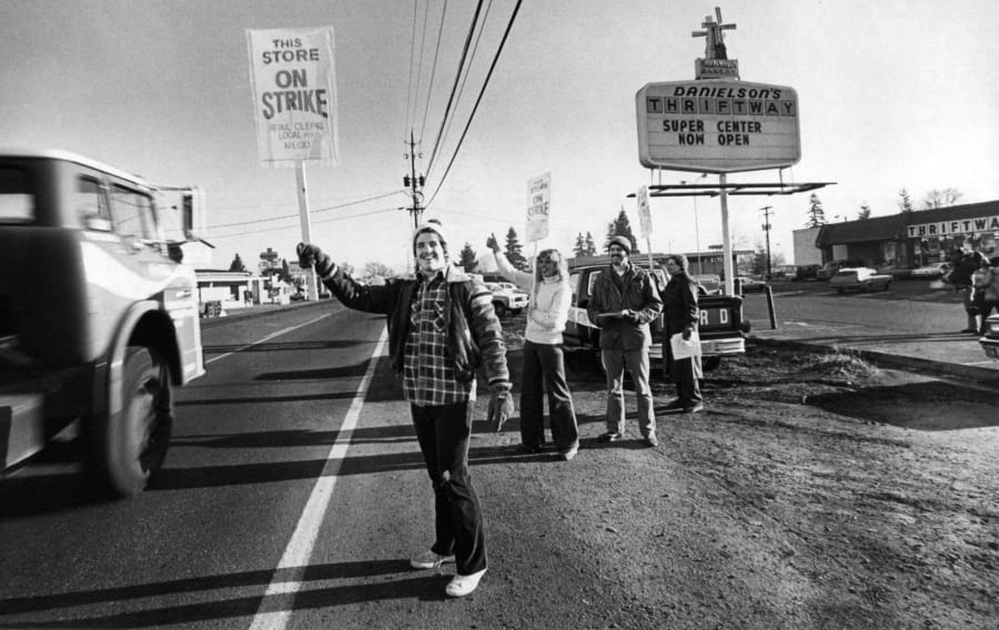 Randy Williams waves a strike sign at a passing truck outside a grocery store on Fourth Plain Boulevard and 109th Avenue in December 1980. Williams was participating in a retail workers strike.