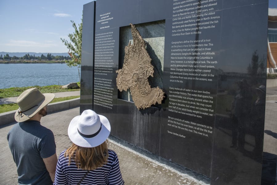 Tom Pearson, left, and Kathryn Pearson of Vancouver examine the Columbia River water feature at The Waterfront Vancouver last week. Water deposits can be seen staining the bottom of the granite and copper monolith after a month of public use.