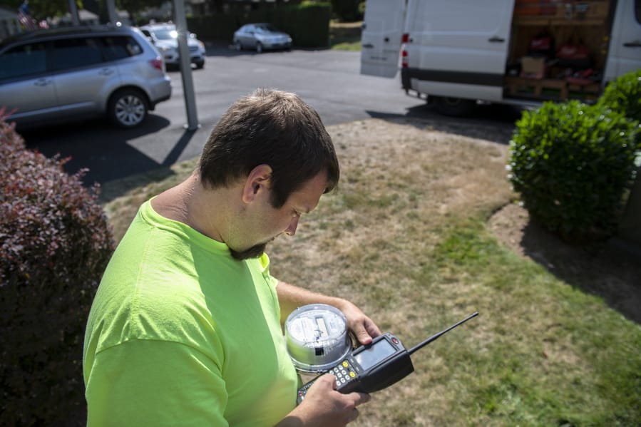 Joe Cryblskey, a Clark Public Utilities automated meter reading driver, uses a manual meter reader to look at customer usage, while covering his route in the Salmon Creek and Felida neighborhoods on Sept. 6. That particular meter was being taken apart for a new electrical panel, causing a failure reading for Cryblskey. Cryblskey said that he has to manually read about 10 meters throughout the day. Cryblskey, 34, has worked for the utility since he graduated high school.
