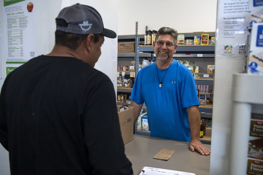 Volunteer Ray Beresh of Vancouver, right, greets a client at FISH Westside Food Pantry of Vancouver. "The outpouring of love that goes back and forth, all the hugs and laughs that we share -- it really helps pick me up," Beresh said.