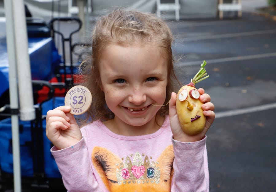 Lilyana Hobbs, 7, of Vancouver shows her vegetable creation Sunday at the Produce Pals program tent at the Vancouver Farmers Market.