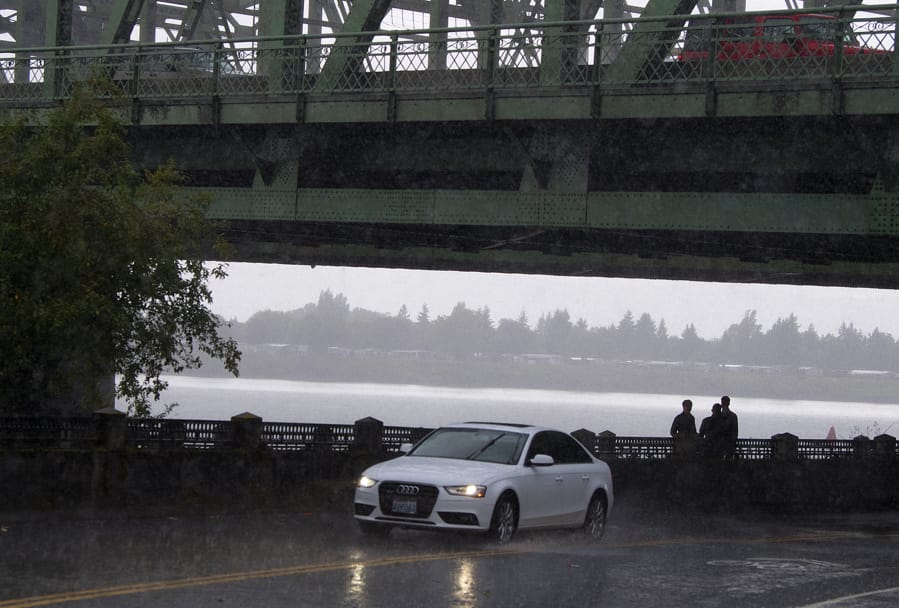 Pedestrians take shelter underneath the Interstate 5 Bridge on Monday afternoon as heavy rains pound the Columbia River waterfront. Expect more unsettled weather Tuesday followed by drier, warmer conditions on Wednesday.