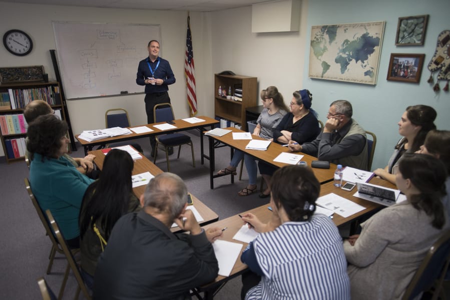 Instructor Ruslan Revutsky of Lutheran Community Services Northwest, standing, reviews the three branches of U.S. government while leading a citizenship class Monday morning. The Vancouver office is celebrating its 25th anniversary on Thursday.