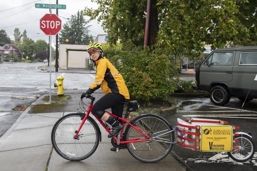 Sally Butts of the Vancouver Bicycle Club checks her left for oncoming traffic before leaving Bike Clark County to pick up leftover produce from the Vancouver Farmers Market on Sunday.