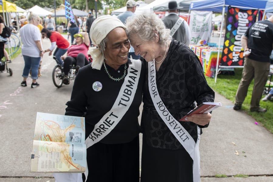 Peace and Justice hero re-enactors Lydia Folwer Newcomb, left, and Sonya Norton share a moment during the 16th annual Peace and Justice Fair at Esther Short Park on Saturday. &quot;Re-enactors are supposed to know about the person they represent,&quot; Norton said. &quot;I actually read up on Eleanor Roosevelt so I can inform visitors.