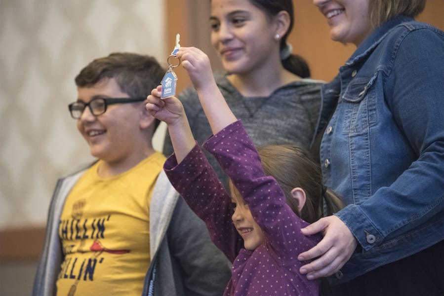 Tony Guzman, 7, from left, Ely Guzman, 11, Anabelle Guzman, 5, and their mother Casey Rice celebrate getting their house key during the Evergreen Habitat for Humanity&#039;s Raising the Roof benefit breakfast at the Hilton Vancouver Washington.